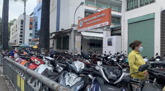 Nhiều bệnh viện ở TP HCM trông giữ xe máy ngoài vỉa hè.