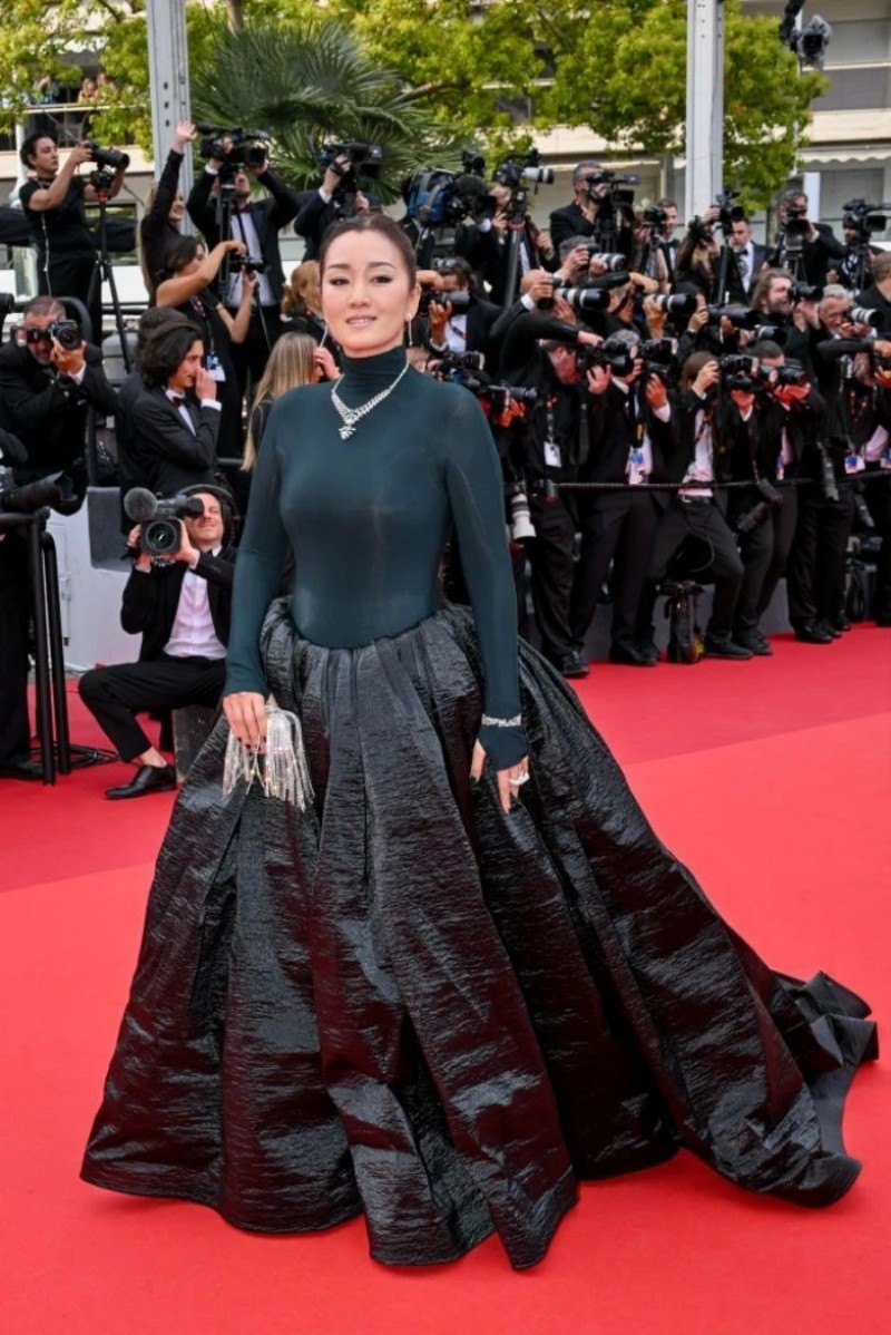 Củng Lợi trên thảm đỏ Cannes với bộ váy đen và chất liệu như “giấy nến” kết hợp trang sức đá quý. Cô là khách mời thường niên, thậm chí được hưởng đặc quyền riêng từ ban tổ chức liên hoan phim. Năm 2019, thảm đỏ Cannes từng tạo khoảng trống trong 3 phút để Củng Lợi có thể tạo dáng ở mọi góc độ, tất cả ống kính đều tập trung vào một mình cô.