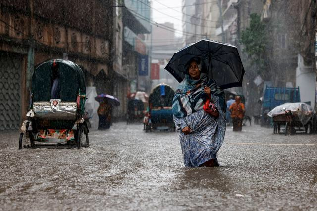 Một người phụ nữ cầm ô khi đi dọc con phố ngập nước trong cơn mưa lớn ở Dhaka, Bangladesh. (Ảnh: REUTERS/Mohammad Ponir Hossain)