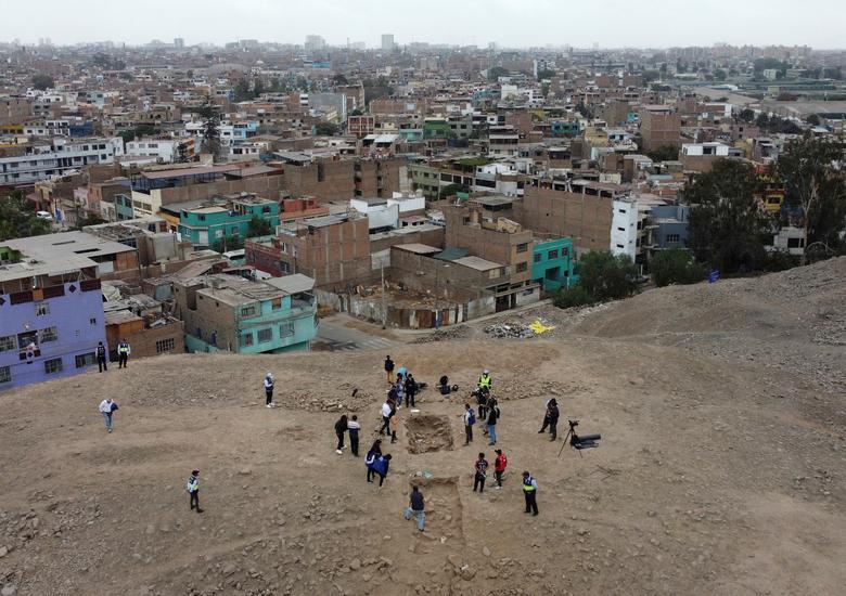 Người dân đứng gần địa điểm khai quật một ngôi mộ từ thời kỳ tiền Colombo với một xác ướp, được cho là thuộc nền văn hóa Manchay phát triển ở các thung lũng Lima trong khoảng thời gian từ 1.500 đến 1.000 TCN, ở Lima, Peru. (Ảnh: REUTERS/Alfredo Galarza)