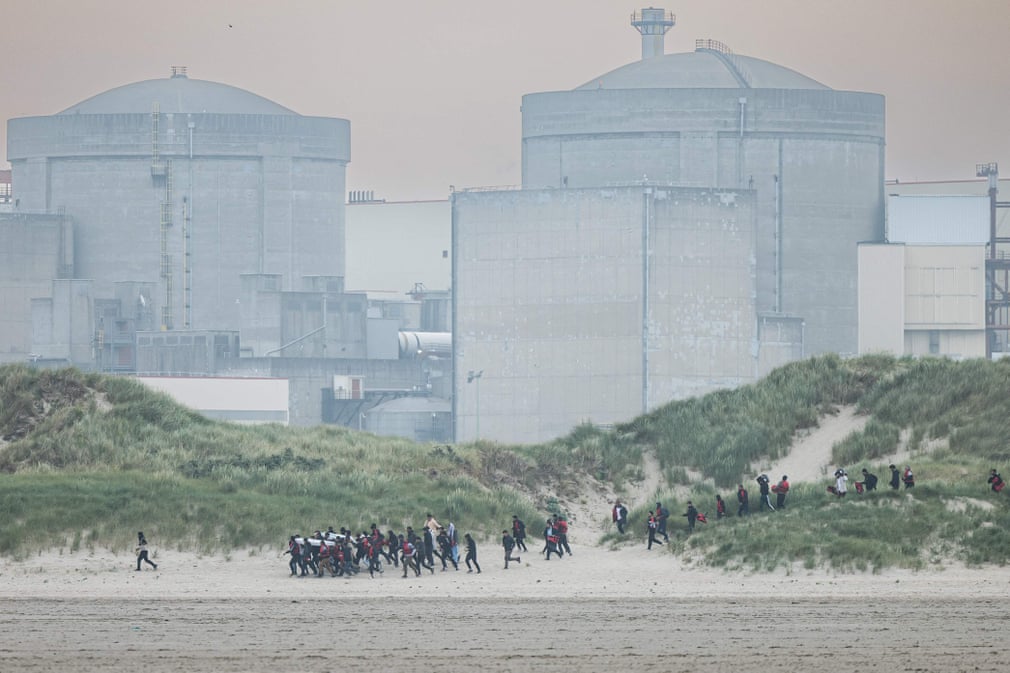 Những người di cư chạy từ cồn cát đến bãi biển gần nhà máy điện hạt nhân Gravelines (Pháp) trong nỗ lực lên thuyền của những kẻ buôn lậu đến Anh. (Ảnh: Sameer Al - Doumy/AFP/Getty Images)