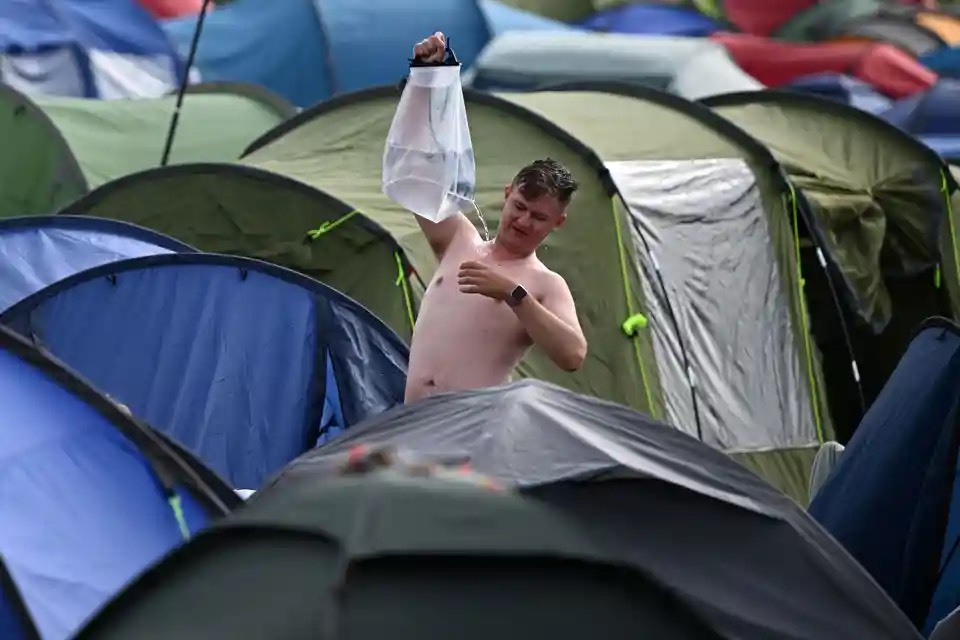 Một người dân sử dụng vòi hoa sen tự chế để tắm vào sáng sớm vào ngày thứ ba của lễ hội Glastonbury. (Ảnh: Oli Scarff/AFP/Getty Images)