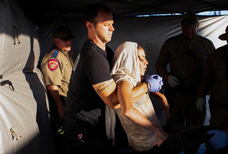 Lính cứu hỏa EMT William Dorsey bế một phụ nữ nhập cư bị kiệt sức vì nóng lên cáng ở thành phố Eagle Pass (bang Texas, Mỹ). (Ảnh: REUTERS/Kaylee Greenlee Beal)