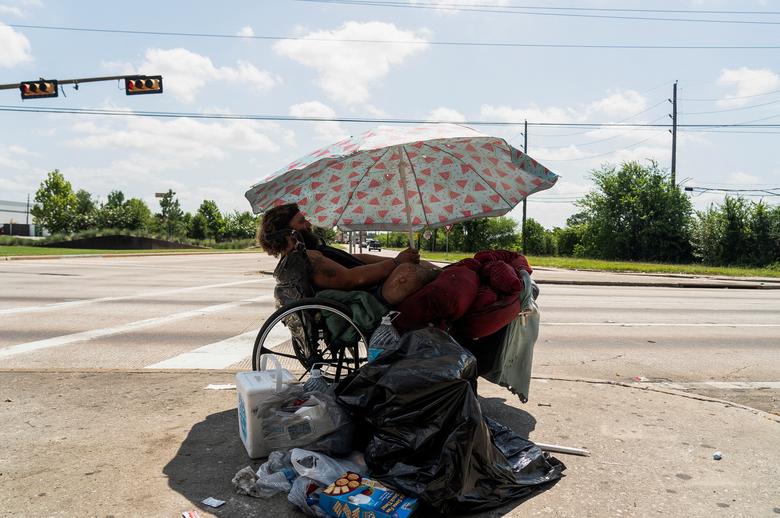 Tony, một người đàn ông vô gia cư, ngồi dưới ô để tránh nắng trong thời tiết khắc nghiệt ở thành phố Houston (tiểu bang Texas, Mỹ). (Ảnh: REUTERS/Go Nakamura)