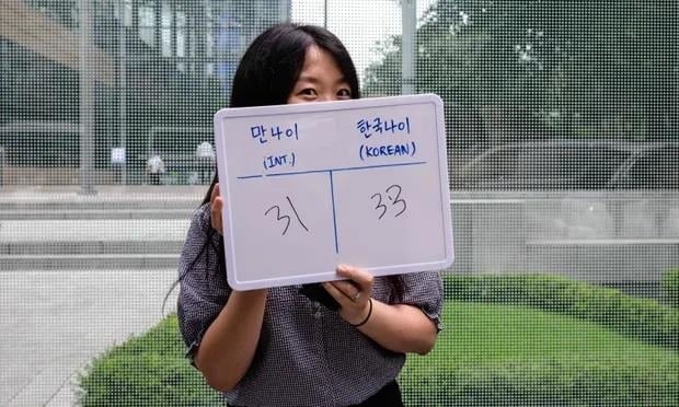 Cô Kim Jin-sil cầm tấm bảng ghi tuổi quốc tế là 31 và tuổi Hàn Quốc là 33. (Ảnh: AFP)