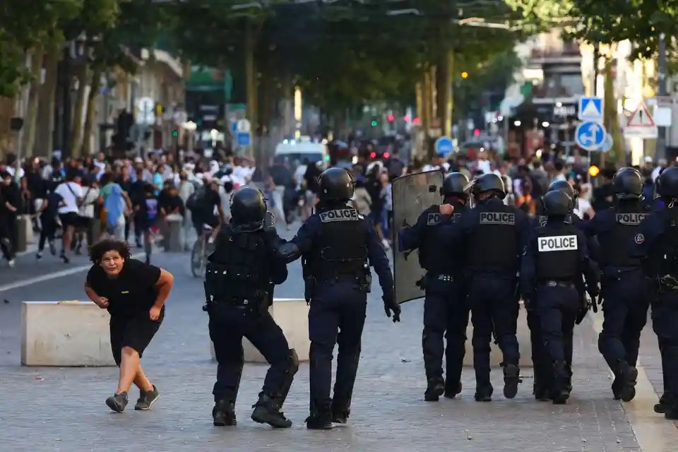 Một cô gái cúi người khi đi ngang qua một nhóm cảnh sát đang chuẩn bị giải tán những người biểu tình bằng hơi cay. (Ảnh: Clement Mahoudeau/AFP/Getty Images)