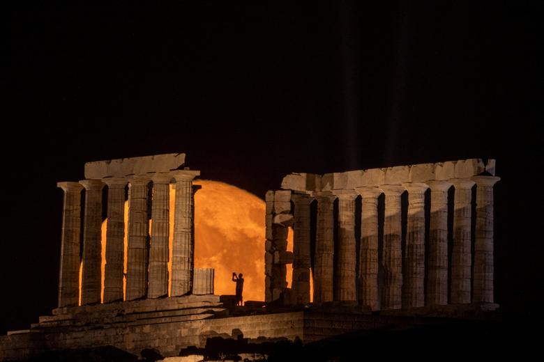 Một người chụp lại khoảnh khắc siêu trăng xuất hiện phía sau Đền thờ Poseidon, ở Mũi Sounion (Athens, Hy Lạp). (Ảnh: REUTERS/Alkis Konstantinidis)