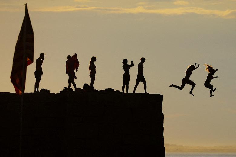 Trẻ em nhảy sóng xuống biển từ bờ đê chắn sóng trước ngày lễ Độc lập ở Gloucester (Massachusetts, Hoa Kỳ). (REUTERS/Brian Snyder)