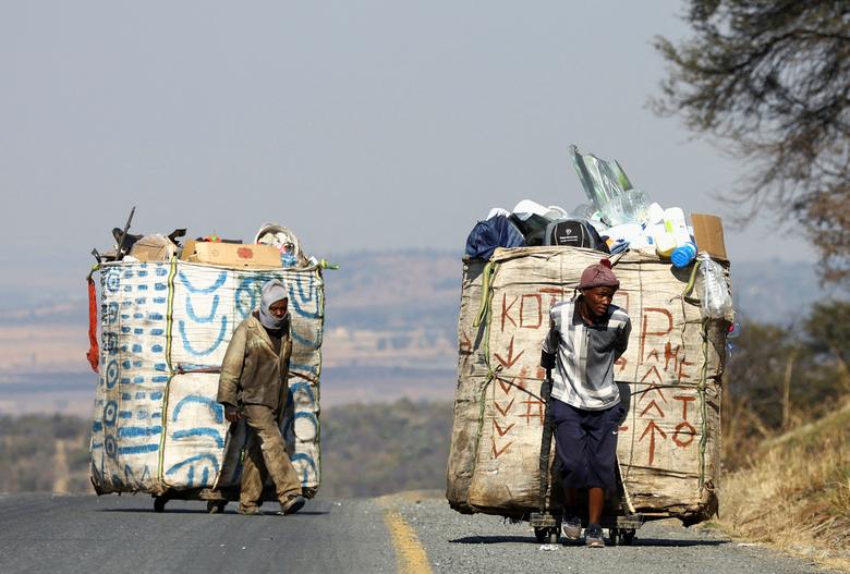 Hai người nhặt rác Steven Lesoona và Thabang Pule kéo những chiếc xe chất đầy vật liệu có thể tái chế, họ đang cố gắng chống lại nạn thất nghiệp ở Naturena (Johannesburg, Nam Phi). (Ảnh: REUTERS/Siphiwe Sibeko)