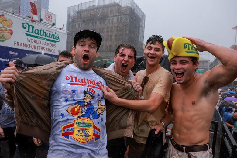 Người dân vui vẻ khi trời đổ mưa vào ngày diễn ra Cuộc thi ăn xúc xích quốc tế nổi tiếng lần thứ tư tại Đảo Coney ở Thành phố New York (Hoa Kỳ). (Ảnh: REUTERS/Amr Alfiky)
