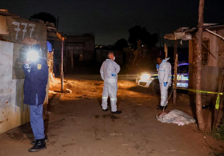 Một sĩ quan cảnh sát và các thành viên đội pháp y tại hiện trường vụ rò rỉ khí gas nghi ngờ có liên quan đến hành vi khai thác trái phép, tại khu định cư Angelo (thành phố Boksburg, Nam Phi). (Ảnh: REUTERS/Siphiwe Sibeko)
