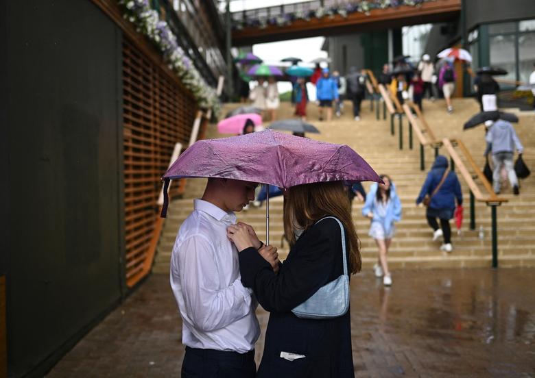 Khán giả đứng dưới ô khi trận đấu ở các sân ngoài trời bị tạm dừng do trời mưa ở vòng đầu tiên của các trận đấu tại Wimbledon. (Ảnh: REUTERS/Dylan Martinez)