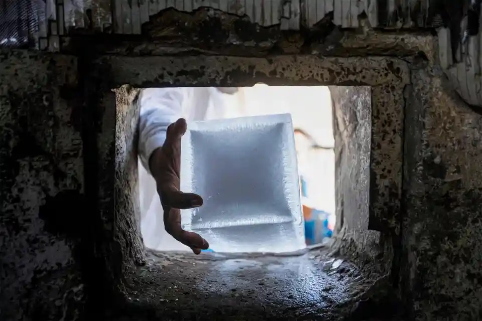 Một công nhân lấy khối đá để bán tại một nhà máy nước đá (Basra, Irac). (Ảnh: Hussein Faleh/AFP/Getty Images)