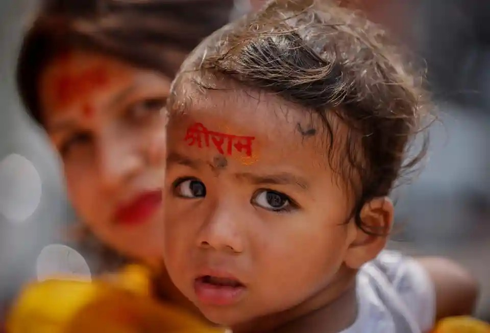 Một người hành hương theo đạo Hindu bế con trai với tên của Chúa Ram được viết trên trán khi họ đến thăm công trường xây dựng đền thờ Ram (Ấn Độ). (Ảnh: Adnan Abidi/Reuters)