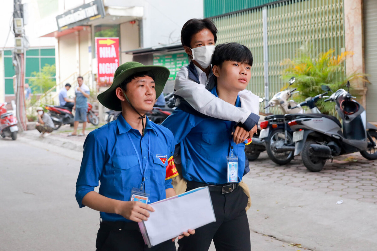 Em Chính được 2 tình nguyện viên tại điểm thi Trường THCS Đông Ngạc (quận Bắc Từ Liêm, Hà Nội) hỗ trợ vào điểm thi. (Ảnh Phan Chí Hiếu)