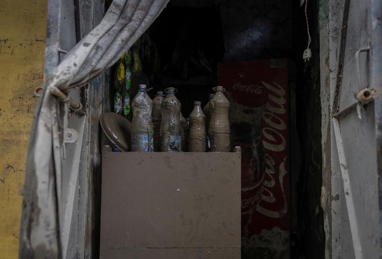 Những chai nước dính đầy bùn ở một cửa hàng tại New Delhi (Ấn Độ) sau khi nước lũ rút. (Ảnh: REUTERS/Adnan Abidi)