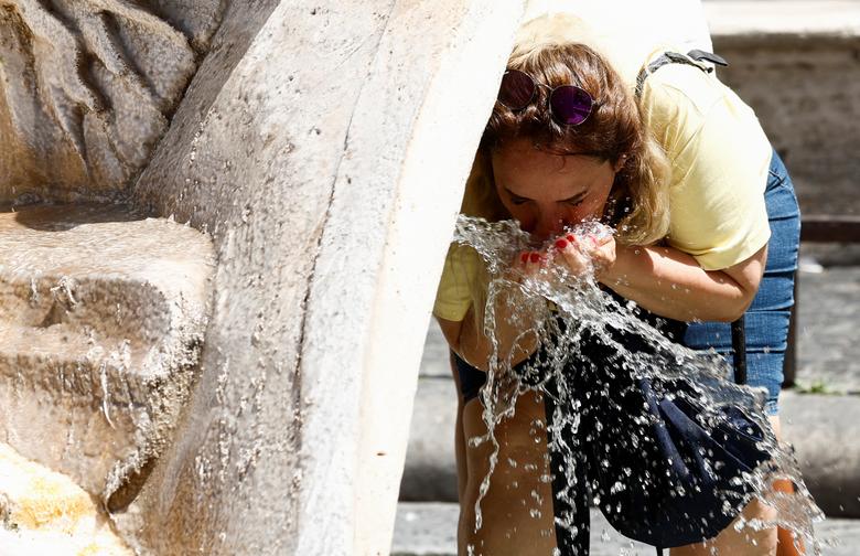Một người phụ nữ rửa mặt ở đài phun nước Fontana della Barcaccia tại Rome (Ý) trong đợt nắng nóng kỷ lục. (Ảnh: REUTERS/Remo Casilli)