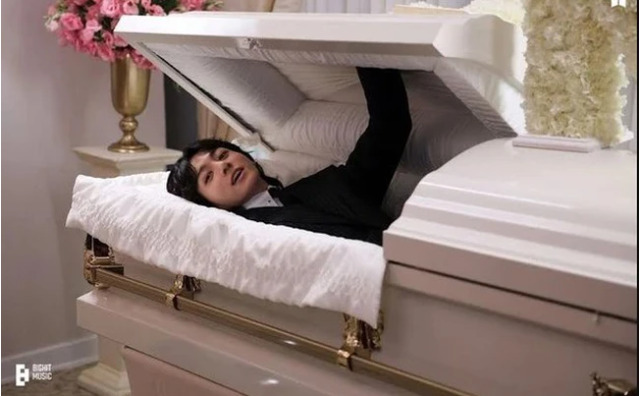 Trong MV 'Seven' nam idol mở nắp quan tài màu trắng 'sống dậy' ngay trong tang lễ để bày tỏ tình yêu bất diệt dành cho cô gái của mình. (Ảnh: Bighit Music)