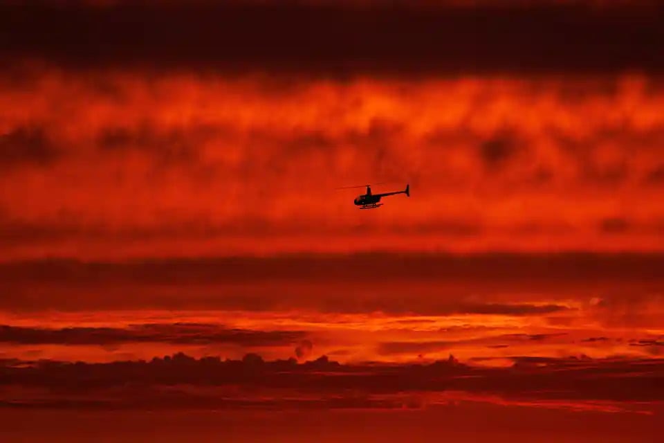 Chiếc trực thăng bay về phía Nam dọc theo bờ biển vào lúc hoàng hôn khi cơn bão Hilary đổ bộ thị trấn Del Mar (California, Mỹ). (Ảnh: Mike Blake/Reuters)