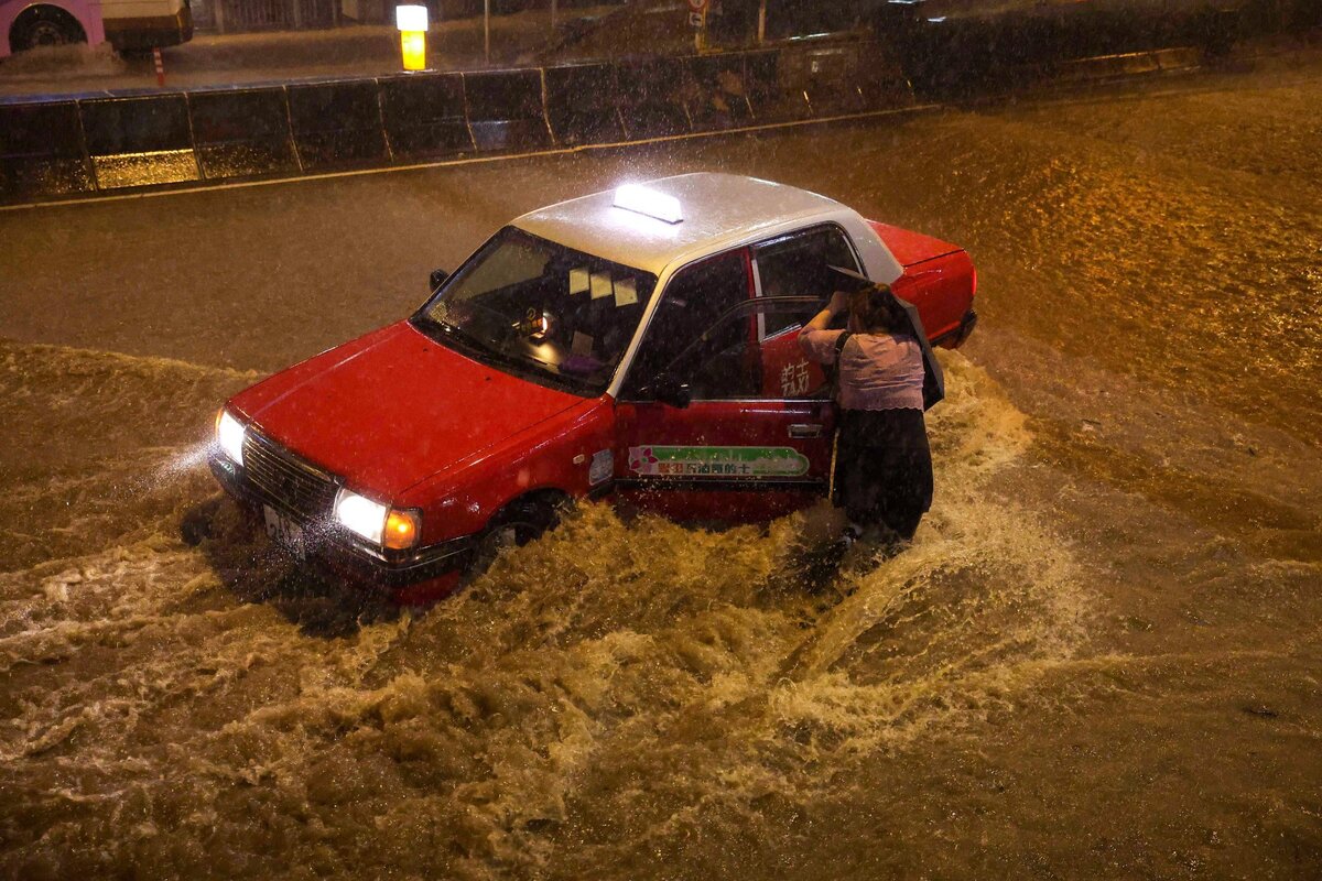 Một người phụ nữ cố gắng bắt taxi dưới cơn mưa lớn. (Ảnh: Edmond So)