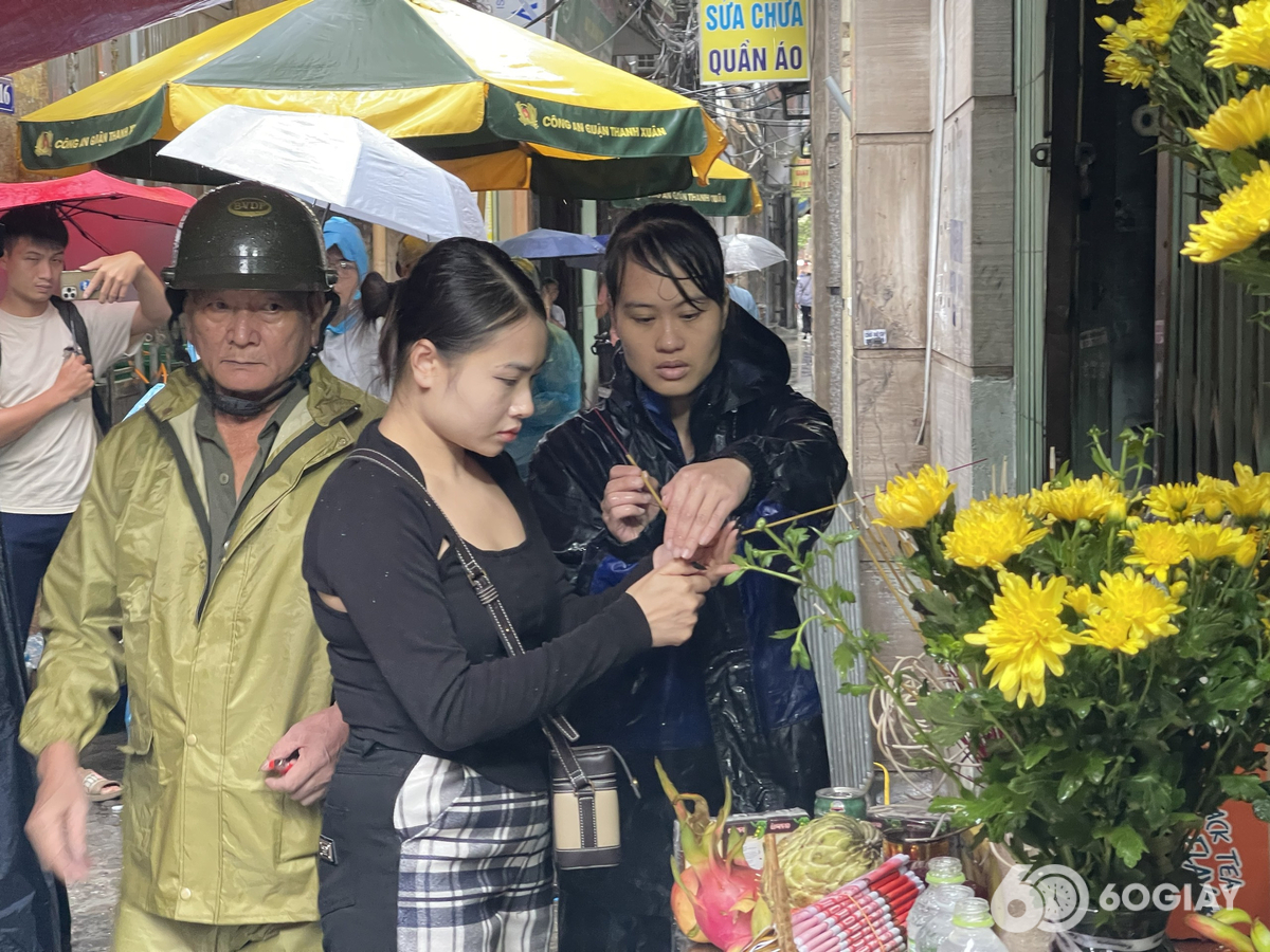Nhiều người đến đặt hoa, thắp hương trước hiện trường vụ cháy chung cư mini ở phố Khương Hạ (TP Hà Nội). (Ảnh: Chí Hiếu)
