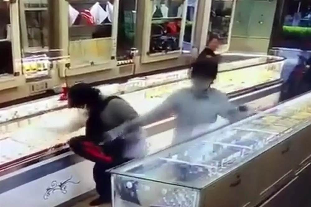 Hai đối tượng mang mũ bảo hiểm, súng vào cướp tiệm vàng Kim Khoa ở Cam Ranh. (Ảnh: Cắt từ clip).