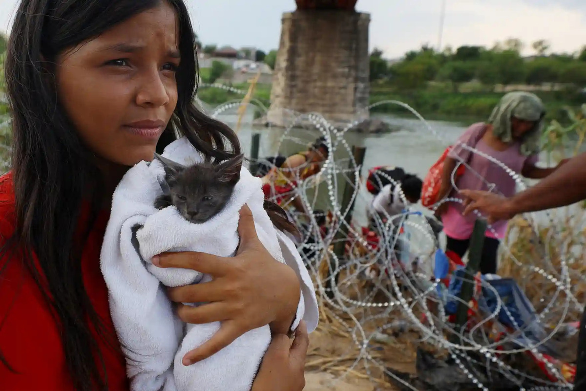 Người phụ nữ Venezuela ôm con mèo mà cô nhặt được sau khi lội qua dòng sông Rio Grande và vượt qua hàng rào thép gai để đến Mỹ. (Ảnh: Brian Snyder/Reuters)