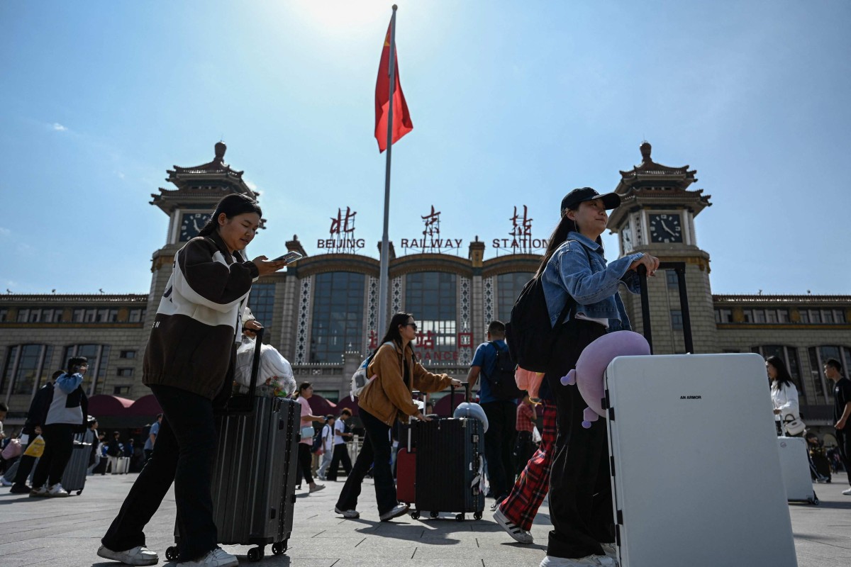 Hành khách đến ga xe lửa Bắc Kinh vào ngày đầu tiên của kỳ nghỉ lễ. (Ảnh: AFP)