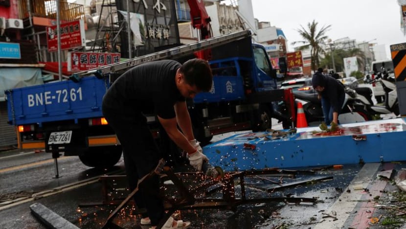 Công nhân cắt một tấm biển bị đổ do gió lớn trước khi chuyển lên xe tải sau khi cơn bão Koinu quét qua Đài Loan.