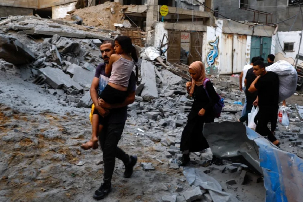 Người dân Dải Gaza đi di tản khi nhà cửa của họ bị phá hủy. (Ảnh: Reuters)