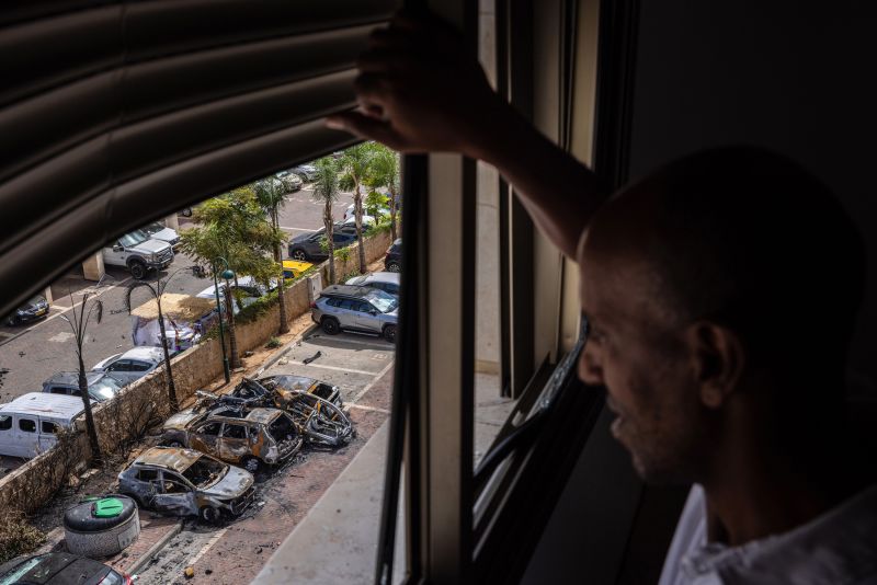 Người đàn ông xem xét thiệt hại sau khi tên lửa bắn trúng bãi đậu xe gần nhà mình. (Ảnh: Tamir Kalifa/The New York Times/Redux)