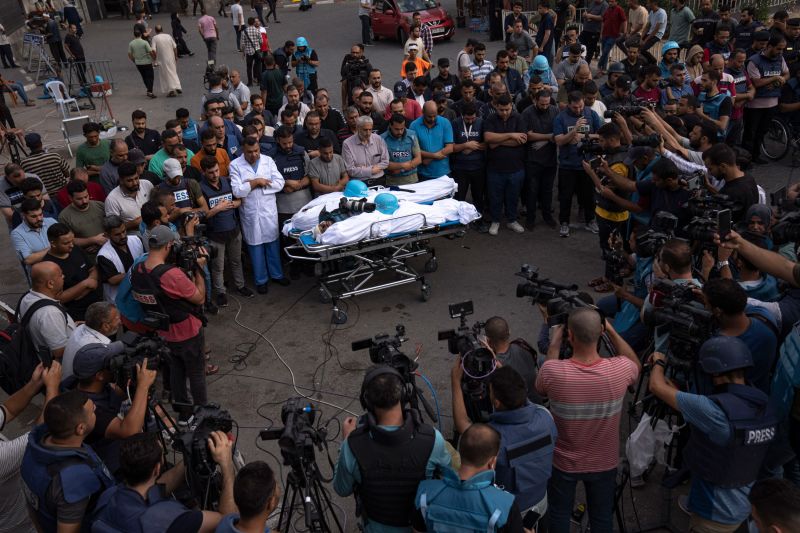 Người dân tụ tập quanh thi thể của hai phóng viên người Palestine, Mohammed Soboh và Said al - Tawil - những người đã thiệt mạng trong cuộc không kích của Israel ở Gaza. (Ảnh: Fatima Shbair/AP)