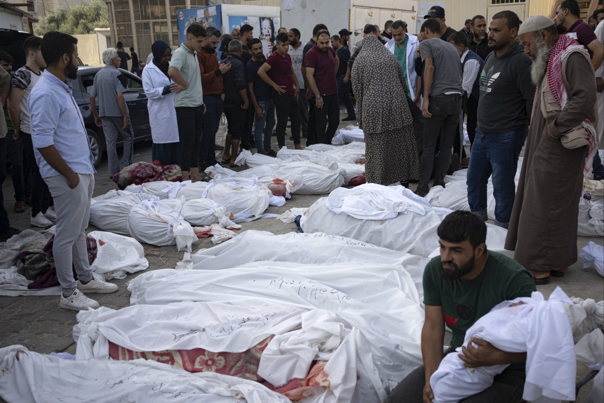 Bạn bè và người thân đứng bên thi thể của những người Palestine thiệt mạng sau cuộc tấn công Dải Gaza của Israel. (Ảnh: AP)