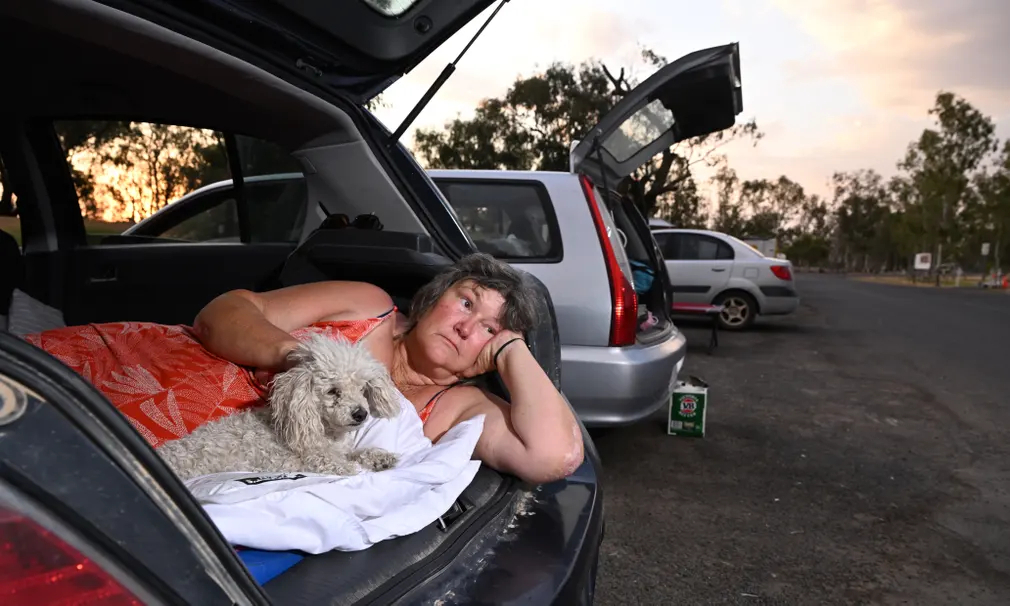 Chị Joanne Hill - một người dân phải sơ tán vì cháy rừng đang nằm trong ô tô cùng chú chó của mình ở Tara (Australia). (Ảnh: Darren England/AAP)