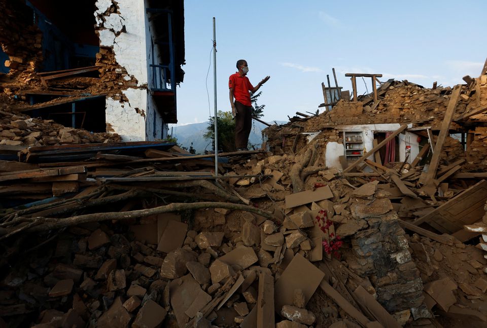 Người đàn ông đứng trên đống đổ nát sau vụ động đất. (Ảnh: Reuters)
