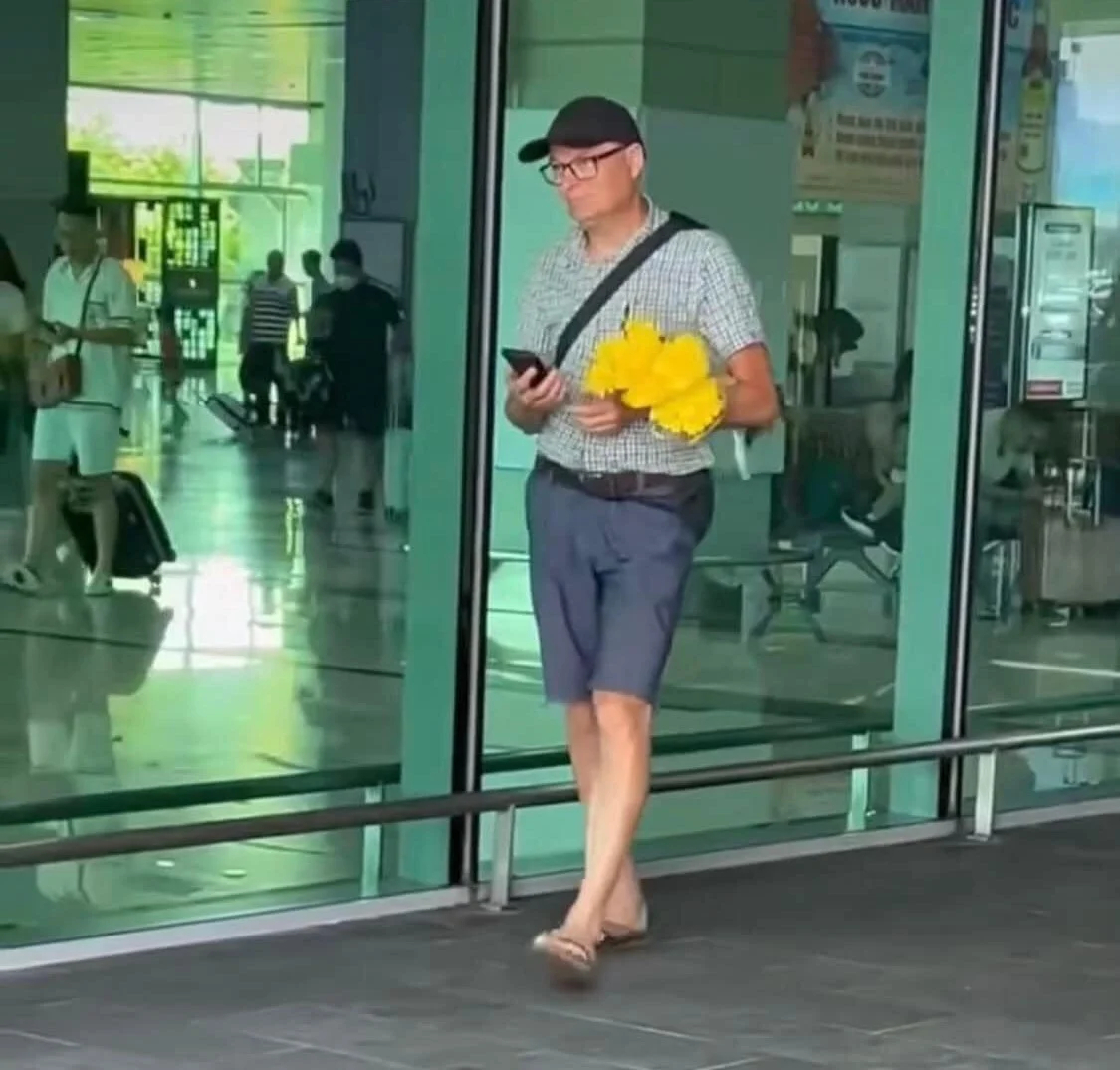 Người đàn ông nước ngoài ôm bó hoa cúc vàng được cho là món quà đón vợ từ Đức về Việt Nam.  