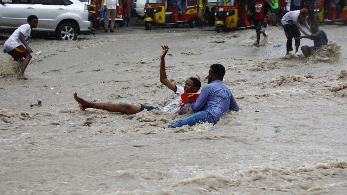 Một người đàn ông cố gắng cứu một cậu bé khỏi dòng nước lũ dữ dội ở thủ đô Mogadishu, Somalia. 