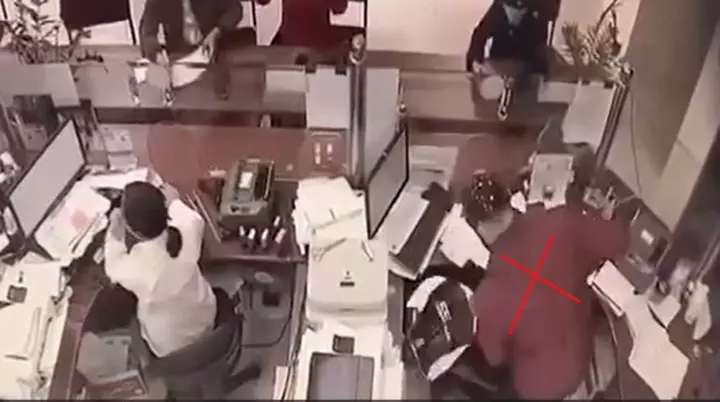 Đối tượng mặc áo màu đỏ, xông vào ngân hàng uy hiếp nhân viên được camera an ninh ghi lại. (Ảnh chụp từ clip)    