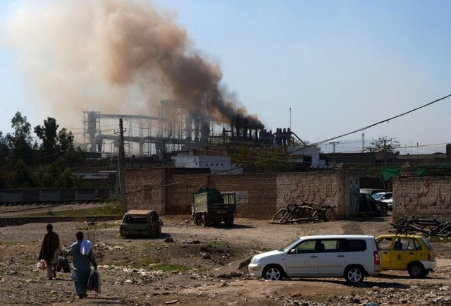 Người dân Pakistan gần một nhà máy ở ngoại ô thành phố Peshawar. (Ảnh: AFP)