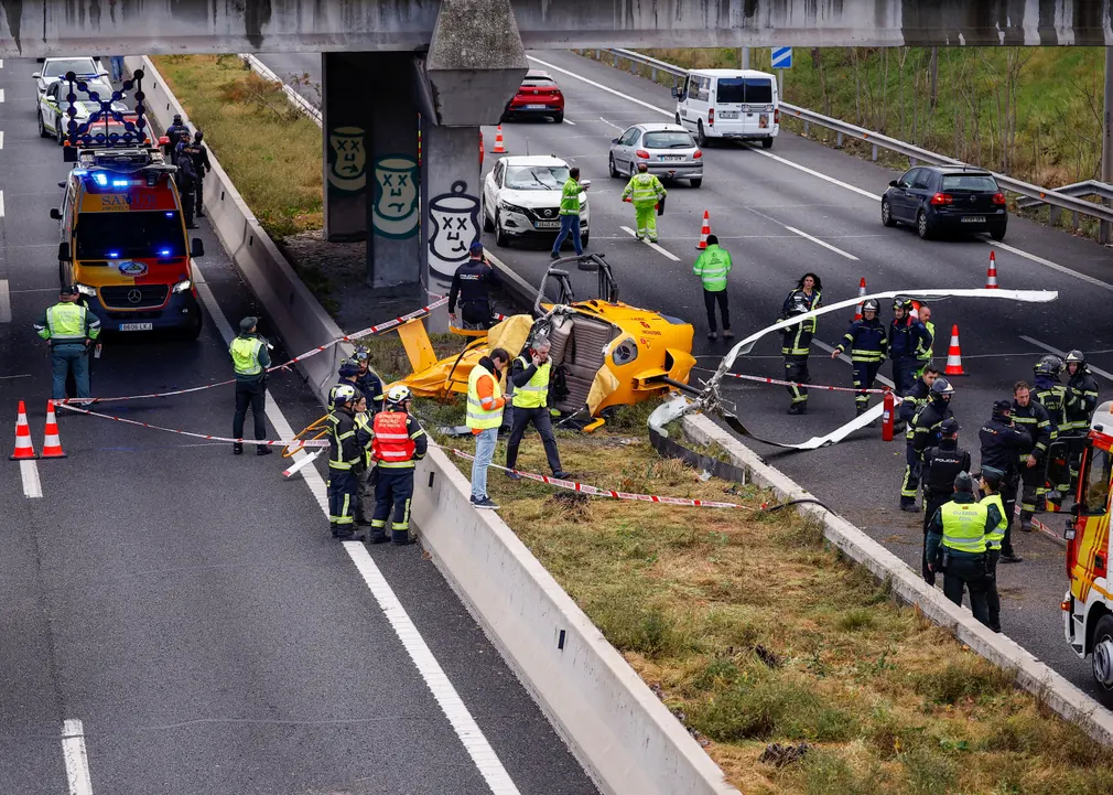 Lực lượng cứu hộ đứng cạnh chiếc trực thăng bị rơi trên đường vành đai cao tốc, đâm vào một ô tô khiến 3 người bị thương ở Madrid (Tây Ban Nha). (Ảnh: Juan Medina/Reuters)
