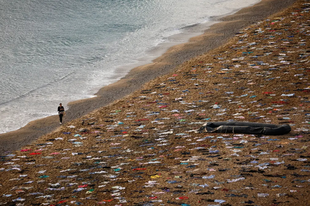 Người phụ nữ đi dọc bờ biển Sant Sebastià khi tổ chức phi chính phủ Open Arms mô phỏng hiện trường vụ đắm tàu để tưởng nhớ những người đã thiệt mạng ở biển Địa Trung Hải vào năm 2023. (Ảnh: Albert Gea/Reuters)