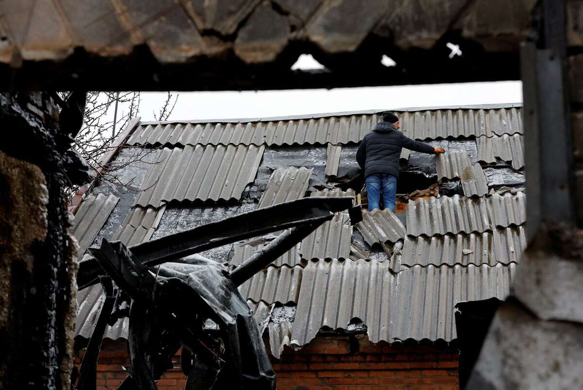 Người dân địa phương kiểm tra mái của một ngôi nhà bị hư hại tại thị trấn Yasynuvata (Ukraine). (Ảnh: REUTERS/Alexander Ermochenko)