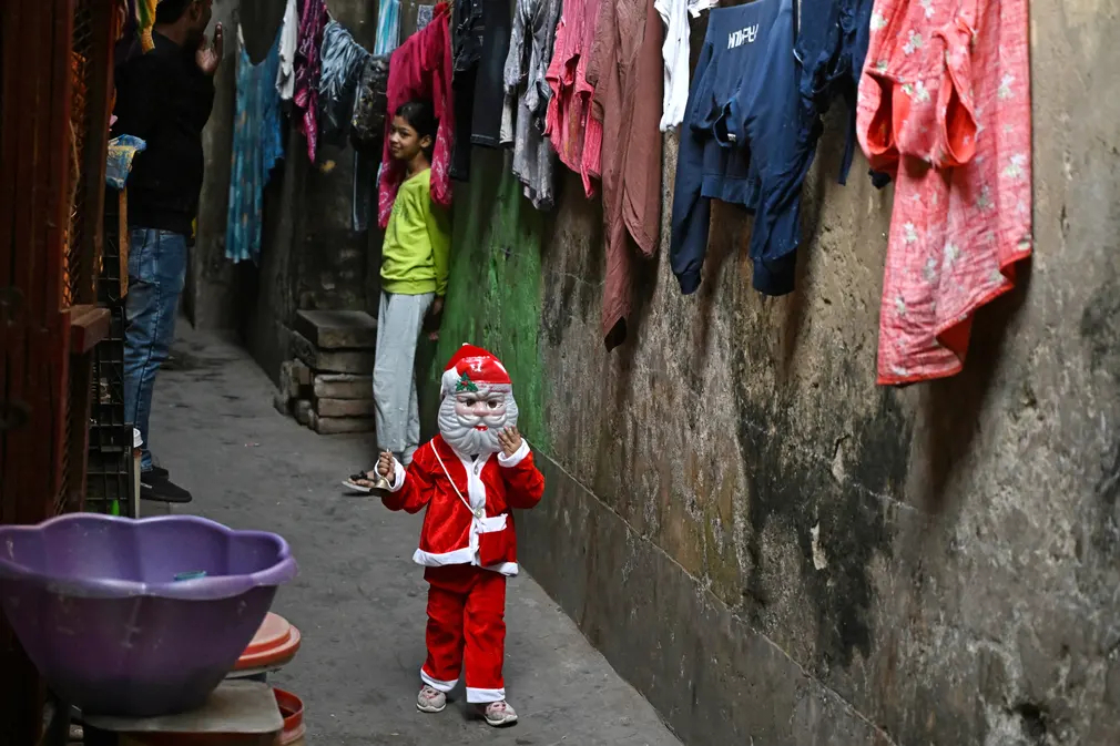 Một đứa trẻ hóa trang thành ông già Noel đi dạo trên đường phố ở Kolkata (Ấn Độ). (Ảnh: Dibyangshu Sarkar/AFP/Getty Images)