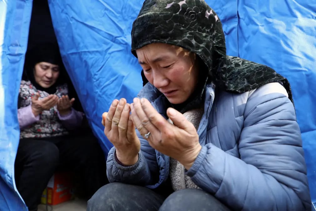 Những người phụ nữ cầu nguyện cho một bé gái 8 tuổi thiệt mạng trong trận động đất ở tỉnh Cam Túc (Trung Quốc). (Ảnh: Xiaoyu Yin/Reuters)