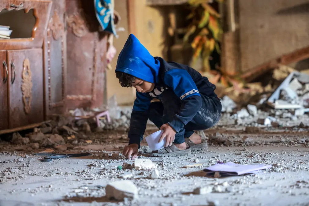 Một cậu bé người Palestine thu thập những mảnh vỡ sau vụ ném bom của Israel ở phía Nam Dải Gaza. (Ảnh: Mohammed Abed/AFP/Getty Images)