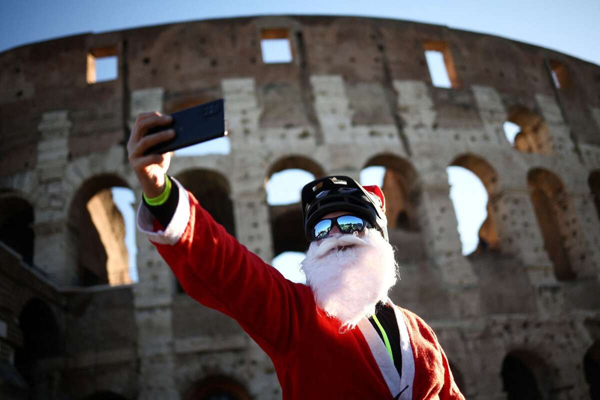 Một người hóa trang thành ông già Noel, tạo dáng chụp ảnh ở Đấu trường La Mã (Rome, Italy). (Ảnh: REUTERS/Guglielmo Mangiapane)