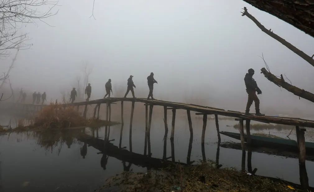 Cảnh sát Ấn Độ tuần tra trên cây cầu gỗ trong ngày lạnh giá và đầy sương mù ở Kashmir. (Ảnh: Farooq Khan/EPA)