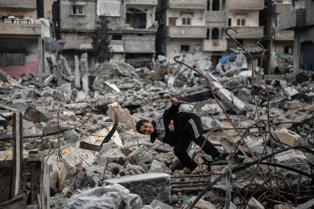 Một cậu bé người Palestine chơi một mình trong đống đổ nát của tòa nhà bị phá hủy sau cuộc tấn công của Israel ở Rafah (Dải Gaza). (Ảnh: Anadolu/Getty Images)