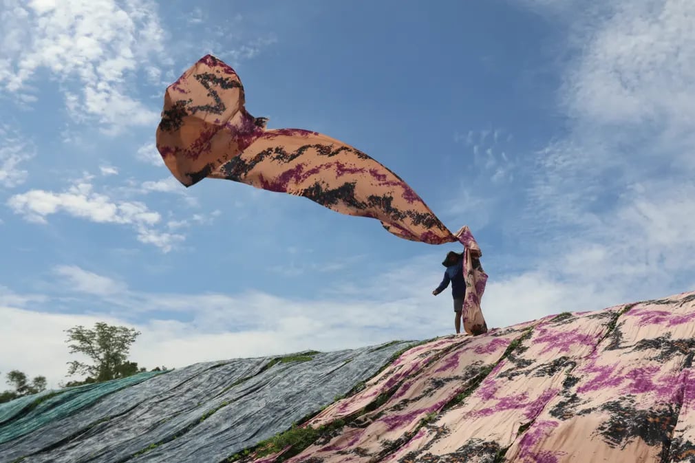 Công nhân phơi loại vải dùng để may quần áo cho phụ nữ Hồi giáo trên bờ sông ở Java (Indonesia). (Ảnh: Garry Lotulung/AFP/Getty Images)
