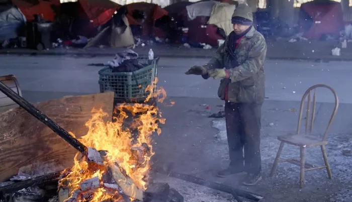 Người đàn ông đốt lửa sưởi ấm gần một khu trại cho người vô gia cư ở bang Chicago. (Ảnh: AP)
